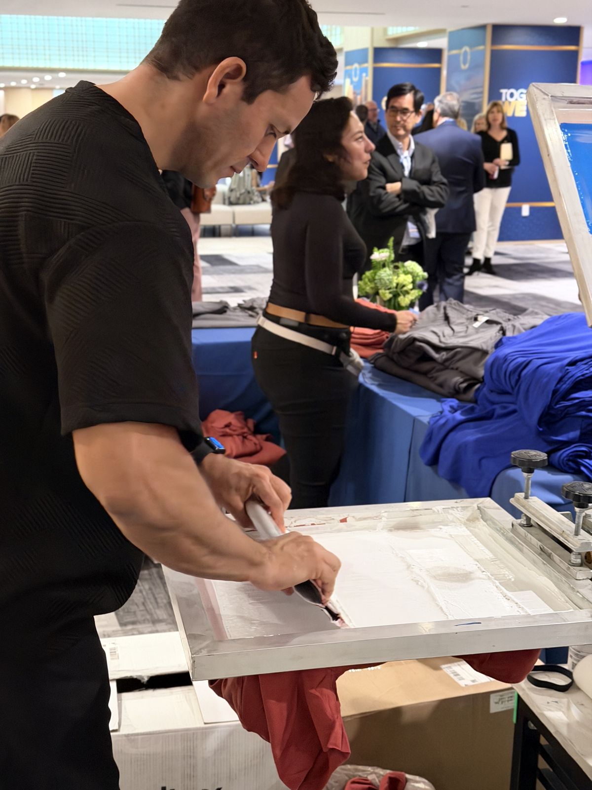 Merch Troop crew member preparing a garment for personalization at a corporate event station